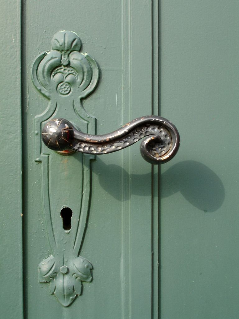 A sturdy green front door with a decorative lever handle and keyhole